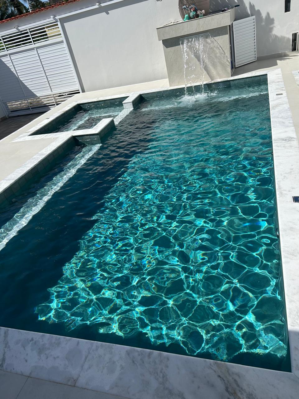 Piscina com água cristalina e cascata tratada por Luan Piscinas